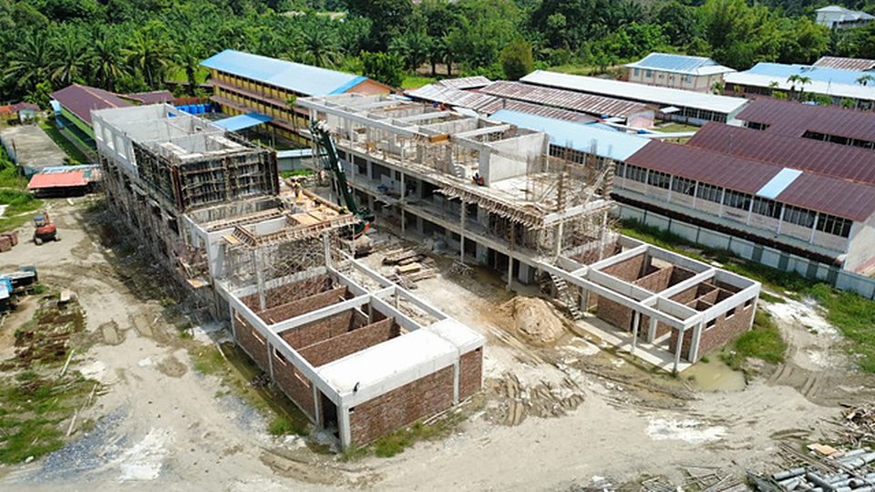 Aerial view of classroom block frames under construction beside existing school buildings