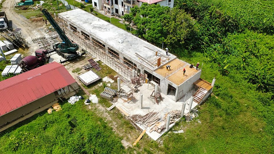 Aerial view of a long single-storey block under construction with a crane
